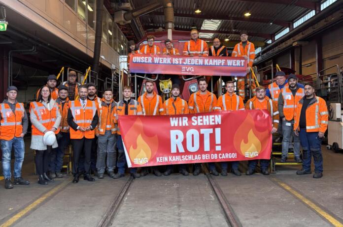 Foto: Gemeinde Bischofsheim, Fotografin Gesa-Sophie Marth. Gemeinsam für den Erhalt des Standorts: Bürgermeisterin Lisa Gößwein und Wirtschaftsstaatssekretär Sönmez mit den Mitarbeitenden des DB-Cargo-Werks in Bischofsheim. Die Belegschaft setzt mit Transparenten ein klares Zeichen gegen die geplante Schließung